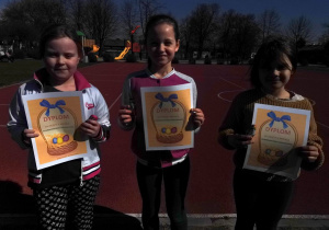 3 dziewczynki z dyplomami - zwyciężczynie klasowego biegu wielkanocnego.